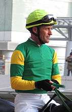 a jockey wearing green and yellow racing silks