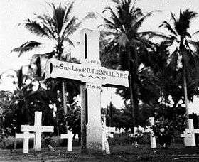 White cross marked "Sqn Ldr P.B. Turnbull, D.F.C." in front of rows of other crosses and palm trees