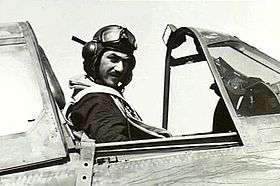 Man in flying helmet sitting in cockpit of military aircraft
