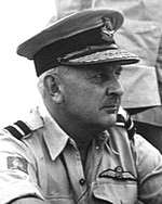 Informal portrait of a caucasian man in light-coloured military shirt with peaked cap, and pilot's wings on left-breast pocket