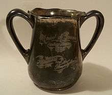 A tarnished, metal, double-handled cup. An inscription, in script, reads: "Univ of Penna/Relay Races/1895/Harvard vs. Pennsylvania."