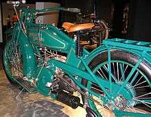 A pristine motorcycle of 1919, painted green with a v-twin engine and footboards.