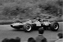 Black-and-white photograph of Jochen Rindt racing in a wingless Cooper Formula One car with his name visibly written on the side of the car