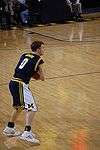 A basketball player in a dark blue uniform has the ball in his hands in the open court.