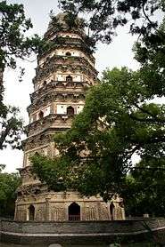 A seven-story, brick, octagonal pagoda, surrounded by trees. Each story is separated by a pair of eaves.