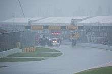 The area is saturated with heavy rain and all cars are stopped behind the safety car.