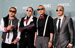 Four Asian-American men, all wearing sunglasses, stand in front of a backdrop.