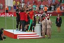 A coloured photograph of the Galatasaray squad standing on the podium and celebrating their Emirates Cup win.