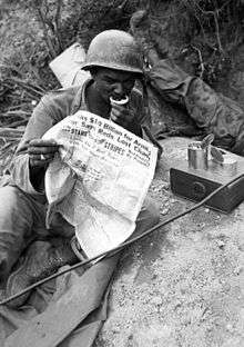 A black soldier rests and reads a newspaper