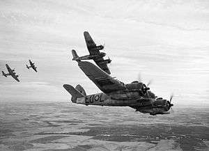 Four twin-engined World War II-era monoplanes in flight over farmland