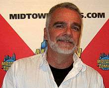 Smiling, gray-bearded man in white shirt