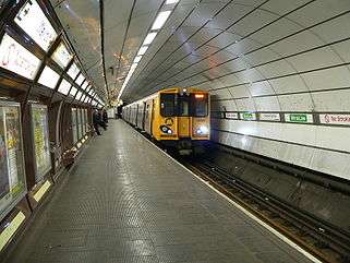 A Merseyrail train painted with a yellow front and grey sides. It is underground at Liverpool Central station.