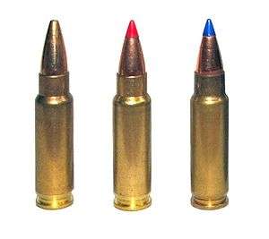 Photo of three 5.7×28mm cartridges as used in the Five-seven pistol. The left cartridge has a plain hollow tip, the center cartridge has a red plastic V-max tip, and the right cartridge has a blue plastic V-max tip.