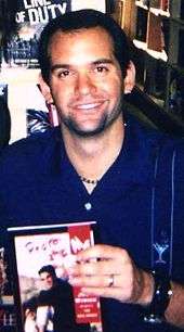 Photograph of Judd Winick of The Real World: San Francisco holding a copy of his novel, Pedro and Me