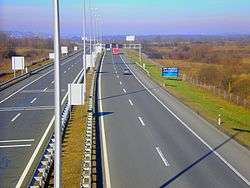 A view of the motorway from a flyover, a variable traffic sign gantry is visible