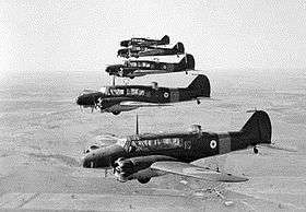 Five twin-engined military monoplanes in flight, line abreast