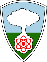  A shield with a white mushroom cloud rising from a red atom against a blue sky