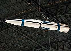 White missile with blue and black stripes hanging from a roof