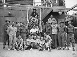 A group of men standing or lying on the deck of a ship, posing for the camera