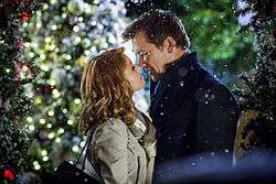 An image of a man and woman about to kiss while snow is falling