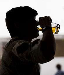 Silhouetted soldier drinking a glass of beer