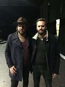 Two members of the band standing beside each other backstage.