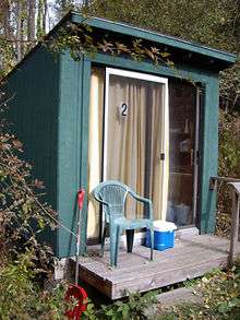 Photo of a small lean-to style wooden hut with a sliding glass front door.