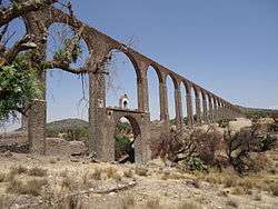 A tall, arched aqueduct in an arid landscape