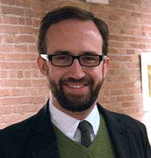 Young, smiling, bearded man with horn-rimmed glasses
