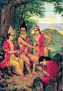 Ahalya (right bottom, seated in a red sari and rising from a stone, bows with folded hands to Rama (left) who is seated with Vishvamitra (centre) on a stone under a tree, in front of her. Lakshamana stands on the right.
