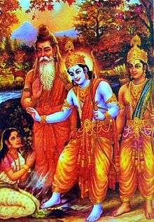 A white sari clad, young Ahalya sits with folded arms in left bottom corner. A blue-hued Rama (central figure) in a yellow dhoti touches his right foot to her, as he blesses her with her right hand and holds a bow in his left. A bearded, saffron-robed Vishvamitra stands to his left. Lakshamana stands to his right.