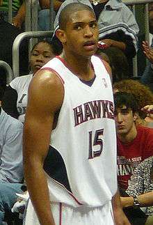 A basketball player, wearing a white jersey with the word "ATLANTA" and the number 15 on the front, stands on a basketball court.