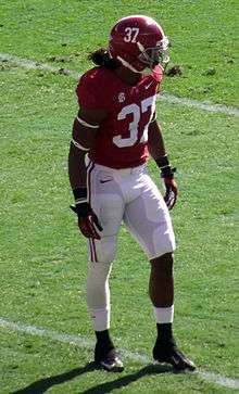 American football player in a crimson jersey and helmet and white pants.