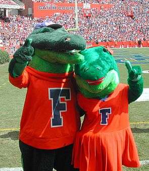 Two alligator mascots with their arms wrapped around each other posing for a photo.