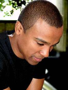 A young man wearing a black T-shirt and short black hair.