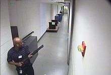 CCTV footage of the shooter in building 197 holding a Remington 870 shotgun.