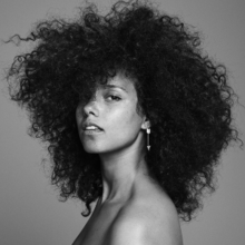 The black and white picture shows woman with black curly hair, wearing a silver earring and looking straight at camera.