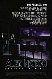 A black poster. Above in bold letters are the lines: "Los Angeles, 1991." "They have come to earth to live among us." "They've learned the language." "Taken jobs." "And tried to fit in." "But there's something about them we don't know." Below, in large typeface is the line: "Alien Nation" and in smaller typeface, the line: "Prepare Yourself"; with the film credits underneath. In the background are three extraterrestrials standing on a street corner. One of the figures is a female standing next to a waste basket and three newspaper stands, holding a jacket over her shoulders. Behind her is a bar that features alien typography on its walls. Two extraterrestrials who are hanging out inside the bar, can be seen through its glass window.