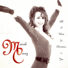 Carey wearing a Santa suit, while posing in an upright position. She has long brown curly hair, and is smiling. The background imagery is beige, with red letters that spell out the song's title.