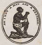 Medallion which shows a slave kneeling and holding his clasped and manacled hands up. Underneath him, a banner says "Am I Not a Man and a Brother?"