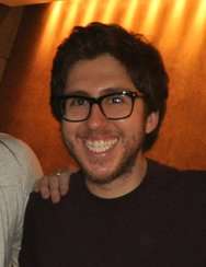Amir Blumenfeld smiling at the camera, with a hand on his shoulder