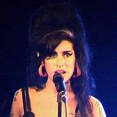 Head and shoulders photograph of Amy Winehouse performing live.