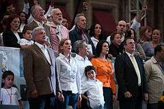 Mancera, in the center of the image, is being accompanied by a group of people that is standing in front of a crowd.