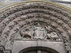 The sculptured section from above a Gothic door. The pointed archway has four molded bands carved with small angels. The triangular section framed by the arch has the figure of Christ surrounded by the Four Heavenly Beasts, the eagle of St John, the winged ox of St Luke, the winged man of St Matthew and the winged lion of St Mark.