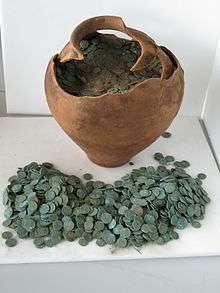 Earthenware pot on a table with coins inside it and in front of it