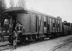 Approximately 4 soldiers, some of whom are armed, posing in front of a heavily armored train car.