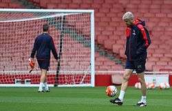 Arsène Wenger kicking a football during an Arsenal training session