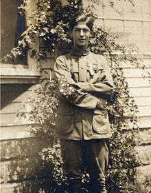 young man in canvas coat and trousers, arms crossed