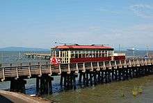 The streetcar passing over a low wooden trestle connected to a dock on the Columbia River
