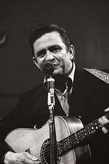 Cash singing into a microphone and strumming a guitar